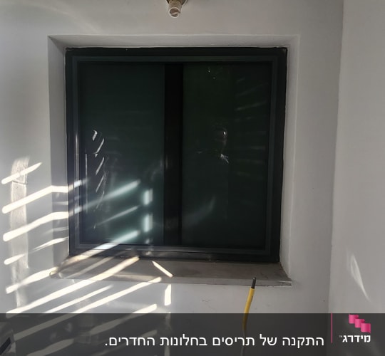 חלון עם מסגרת אלומיניום וקיר לבן